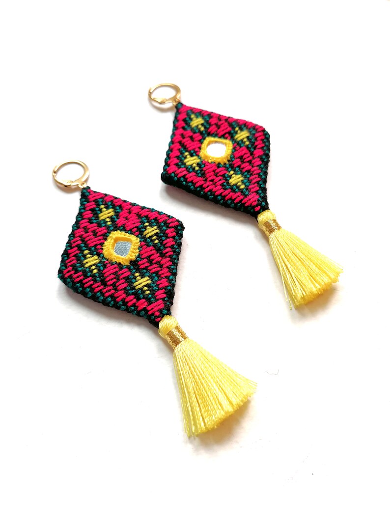Oblique whole-pair view of Baluchi embroidered earrings and yellow tassels